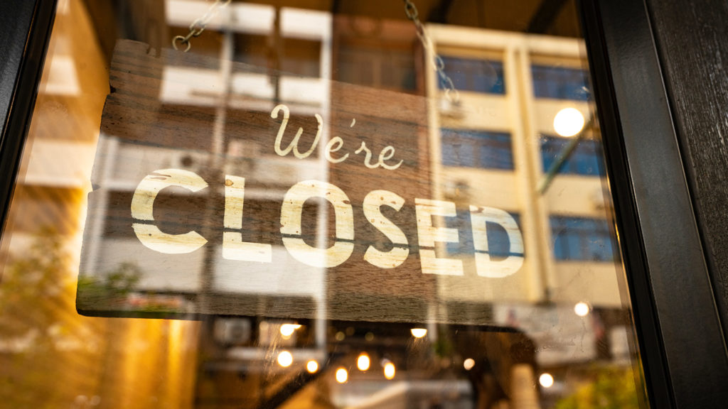 Closed sign hanging in business window.