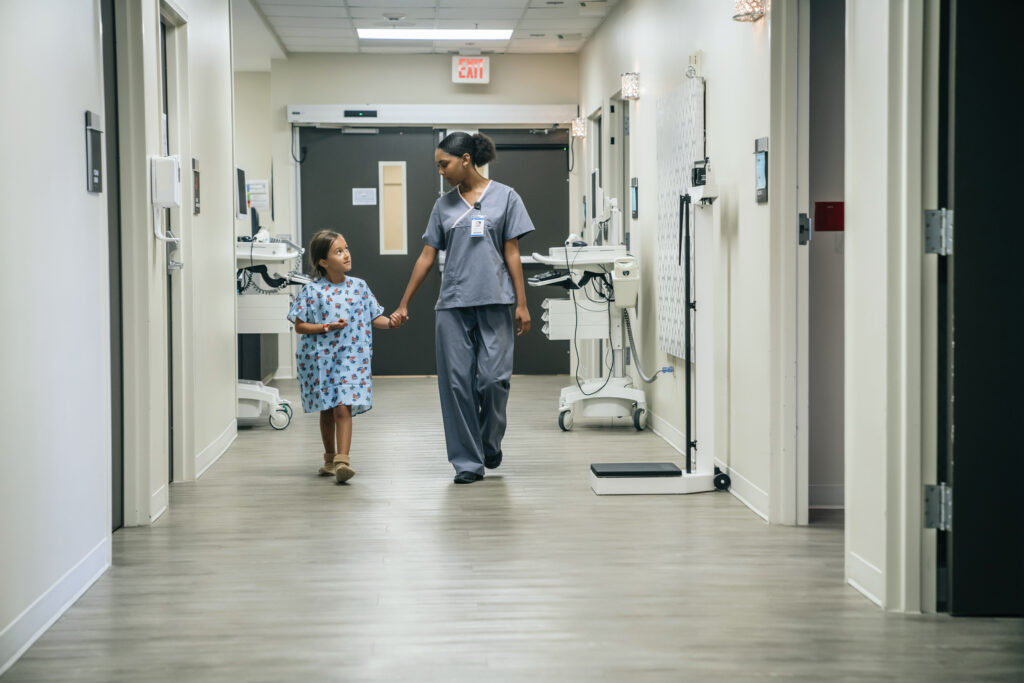 Medical professional holding hands with a child in hospital