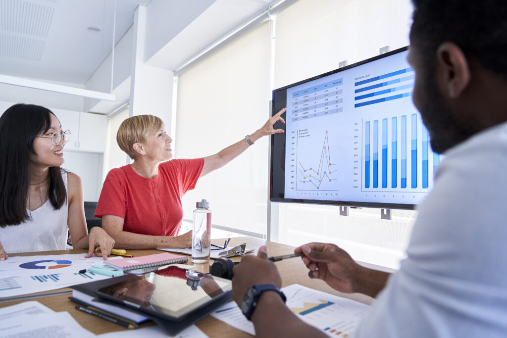 Coworkers examining data on a large screen in the office