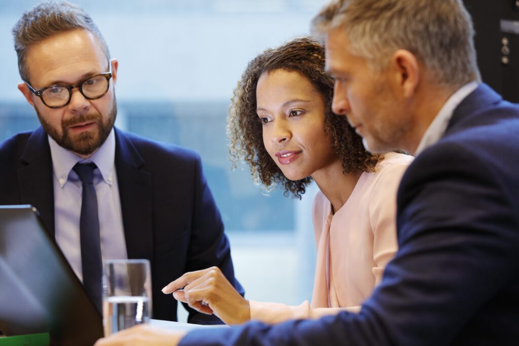 Three colleagues having a discussion in the office while looking at a computer on a desk