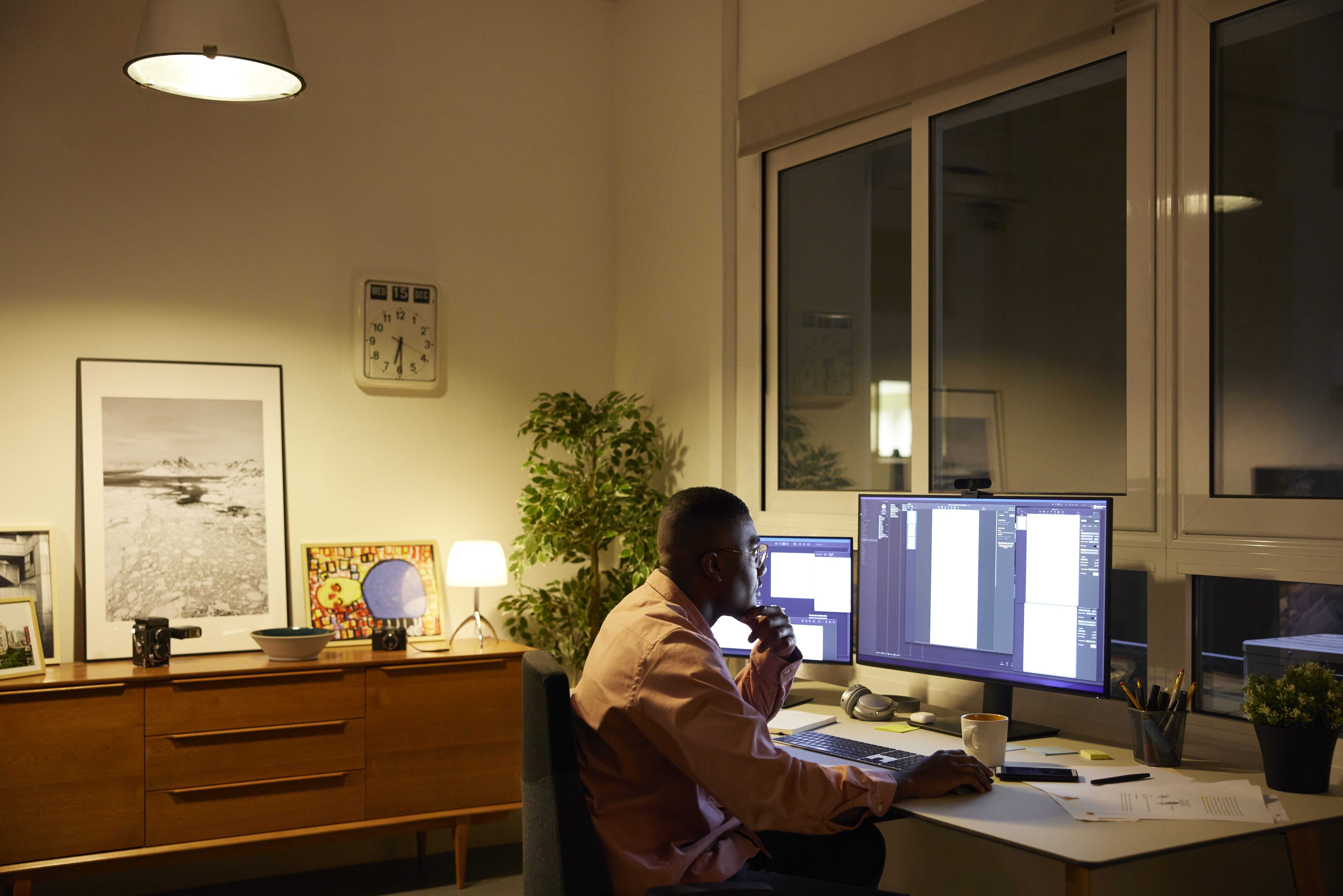 Person using computer at night. Entrepreneur is working late at home office. He is sitting at desk.