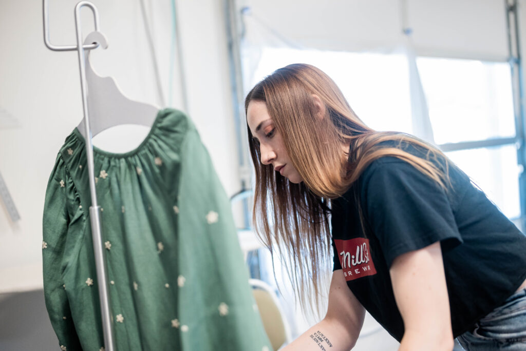 Employee examining a green dress in a fashion boutique