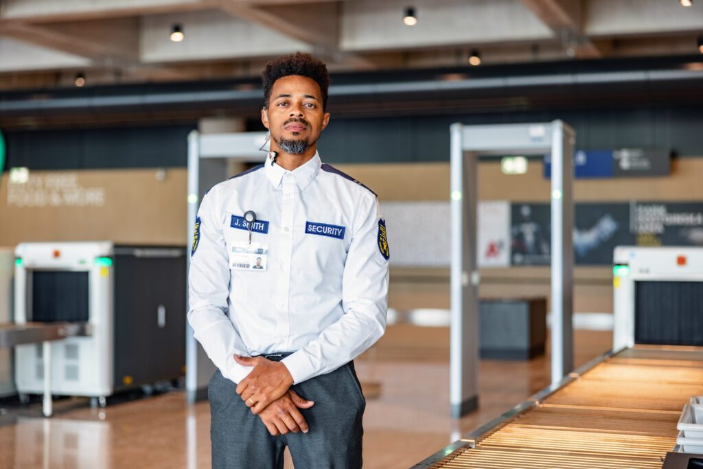 Airport security guard standing by luggage scanners