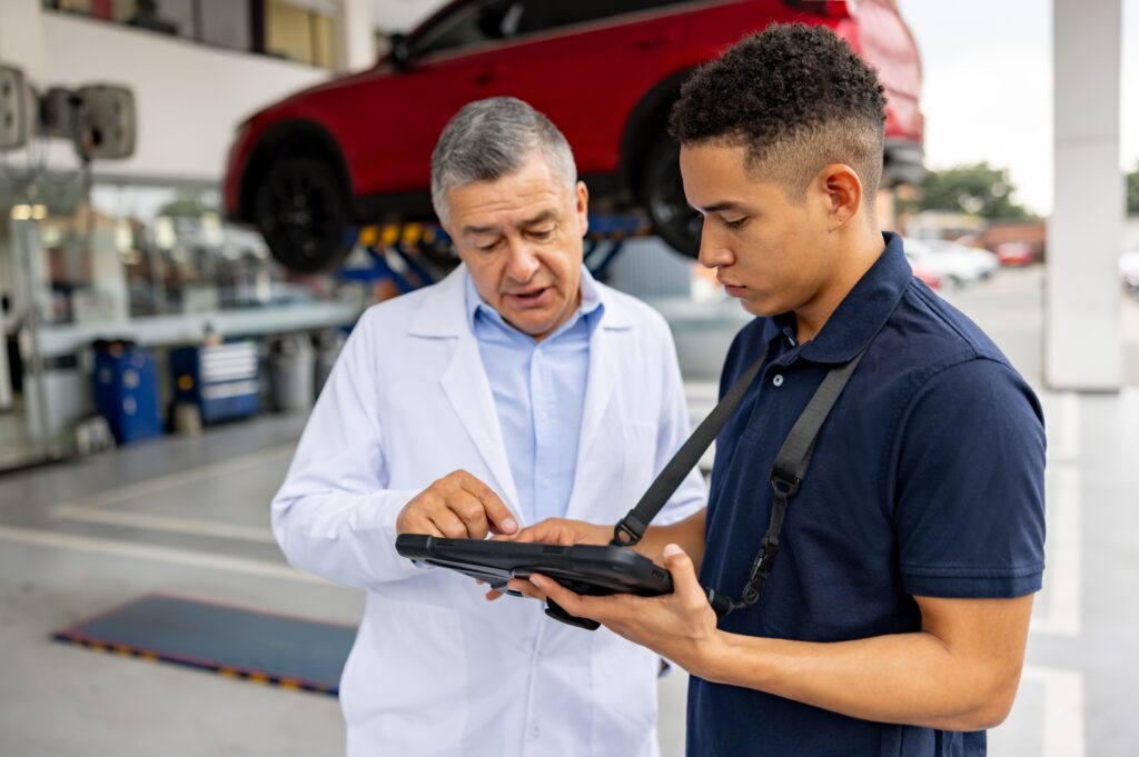 Mechanic showing a diagnosis on a tablet to an engineer at a car garage