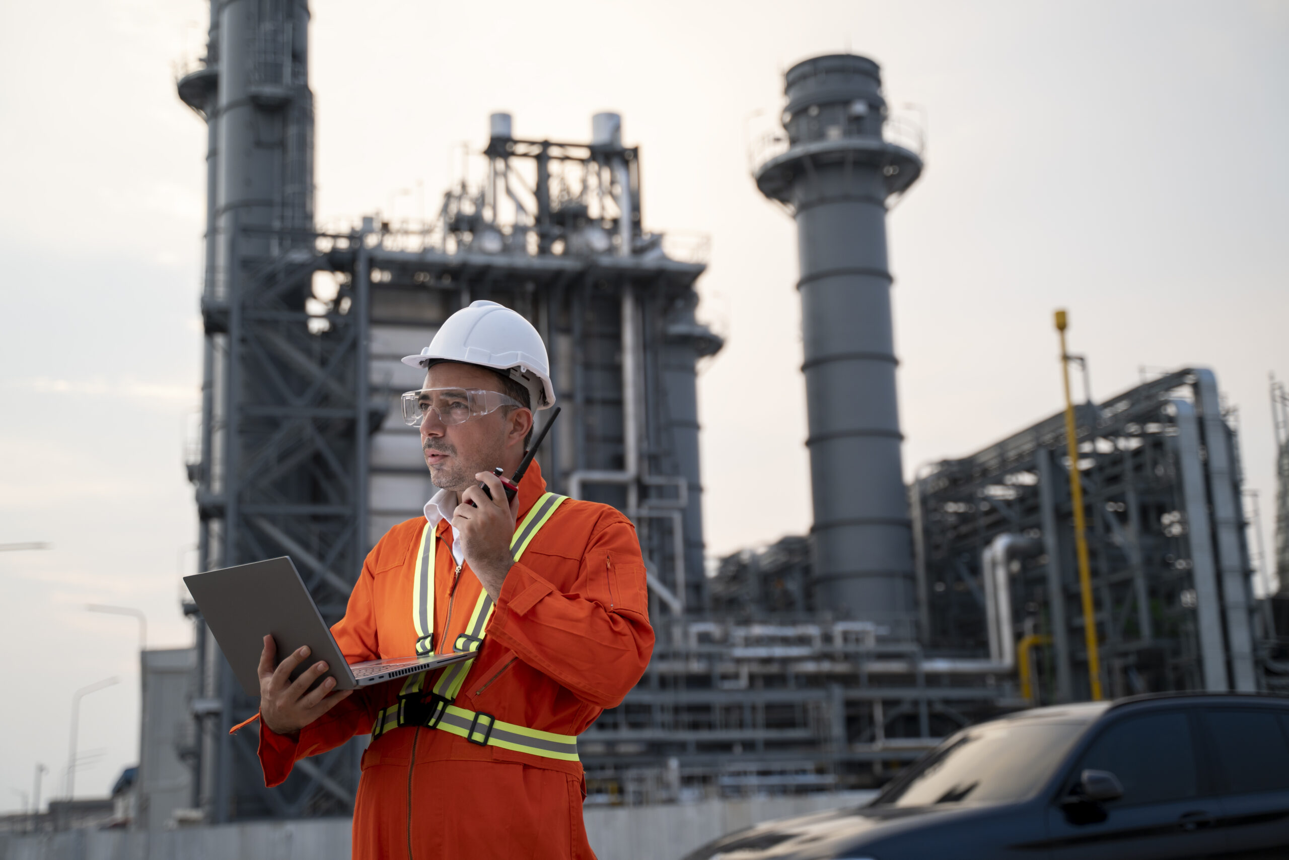 Engineer using laptop in front of manufacturing plant