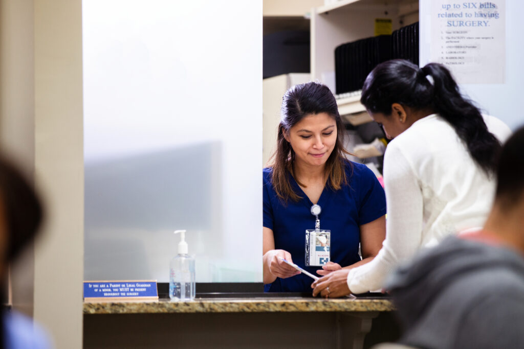 Healthcare receptionist checking in patient at window