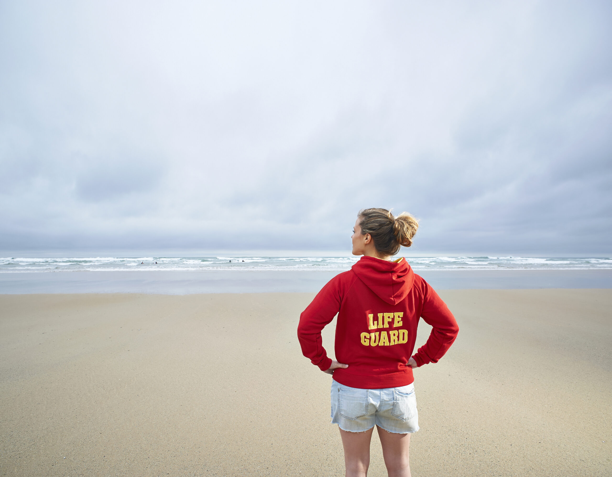 Life guard standing on the beach looking out to the ocean