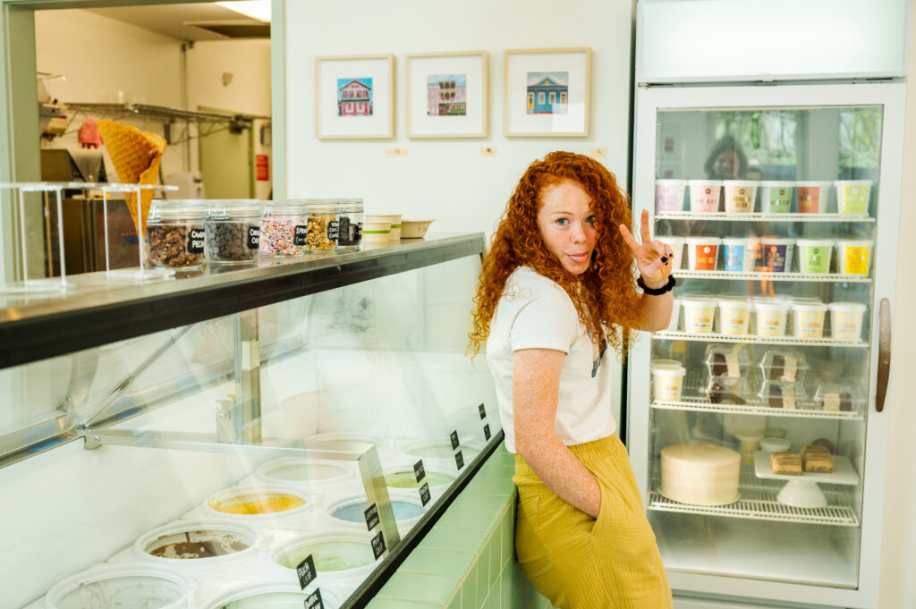 Employee relaxing on the ice cream display case in an ice cream shop, showing the peace sign