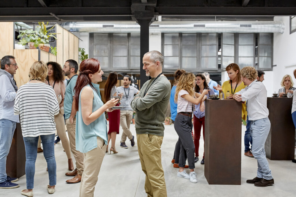 Business people are standing at convention center. Male and female professionals communicating during meeting.