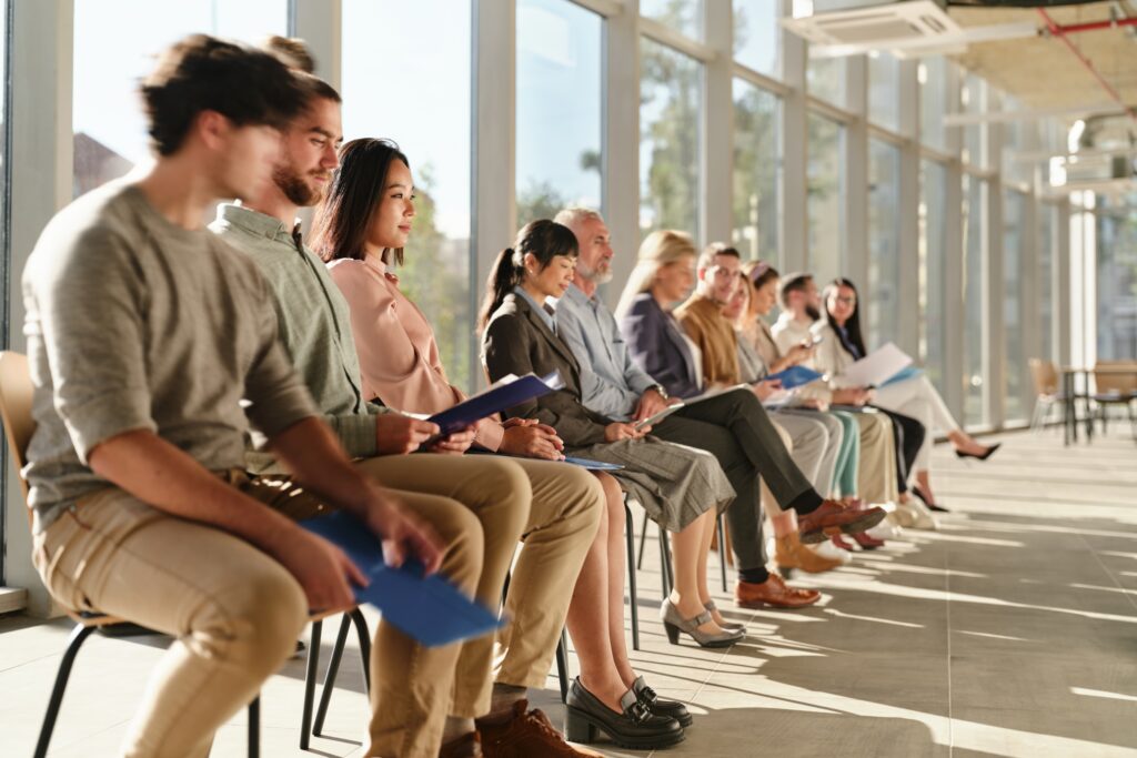 Group sitting in line holding folders at hiring event in office