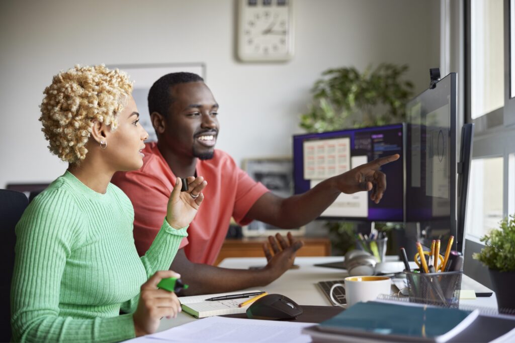 Young colleagues brainstorming at the office in front of multiple computers