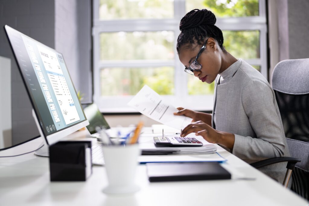 Accountant crunching numbers using a calculator while working at their desk