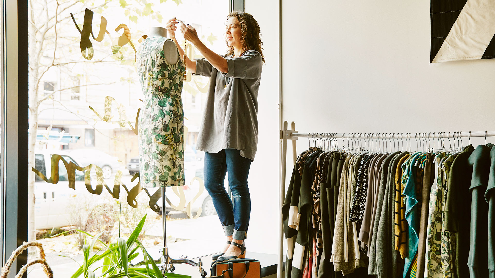 Woman hanging dress on mannequin in a shop window