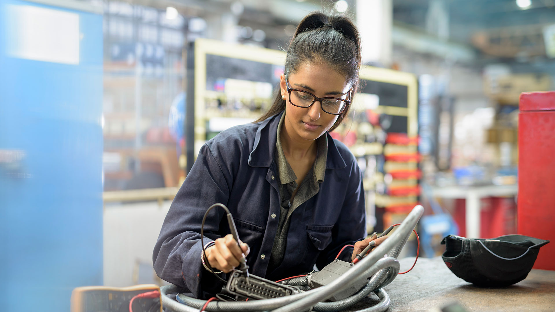 Young mechanic welding a machine part in factory