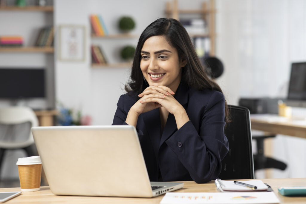 Confident young professional in a virtual meeting smiling at the laptop screen in front of them