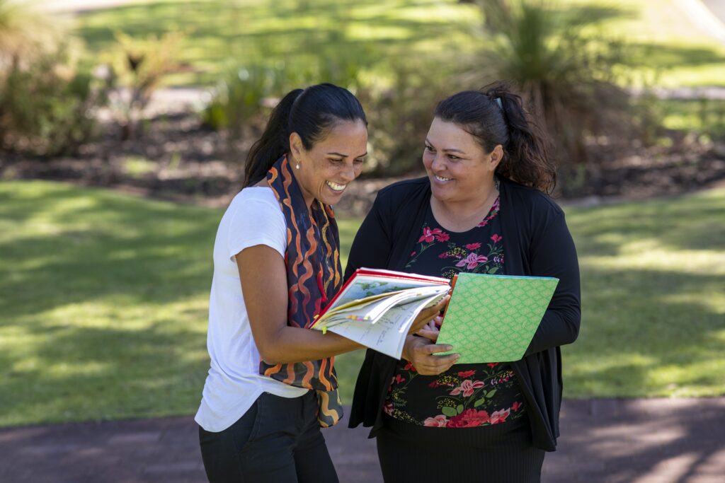 Two people smiling outdoors both holding folders