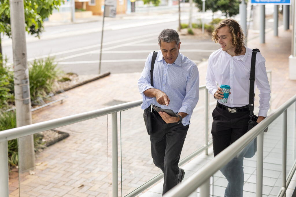 Two people walking and talking outside the office both are wearing business attire