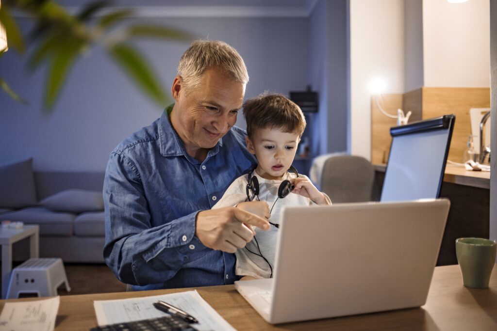 Parents with child on their lap working from home with laptop on desk