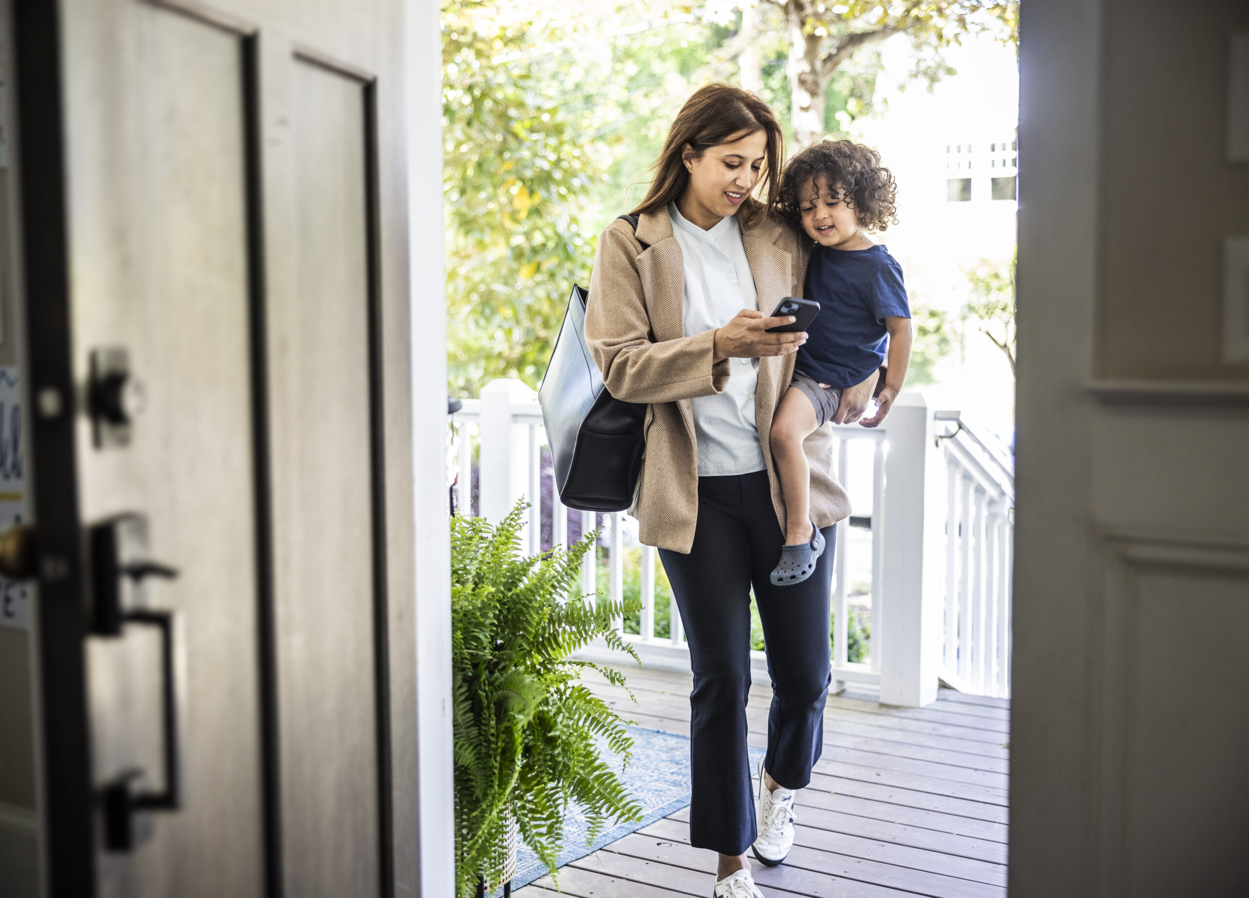 Adulte tenant un jeune enfant tout en regardant son téléphone