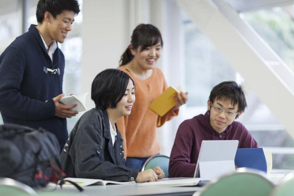 4人の生徒がテーブルを囲んでタブレットを見ながら一緒に勉強している