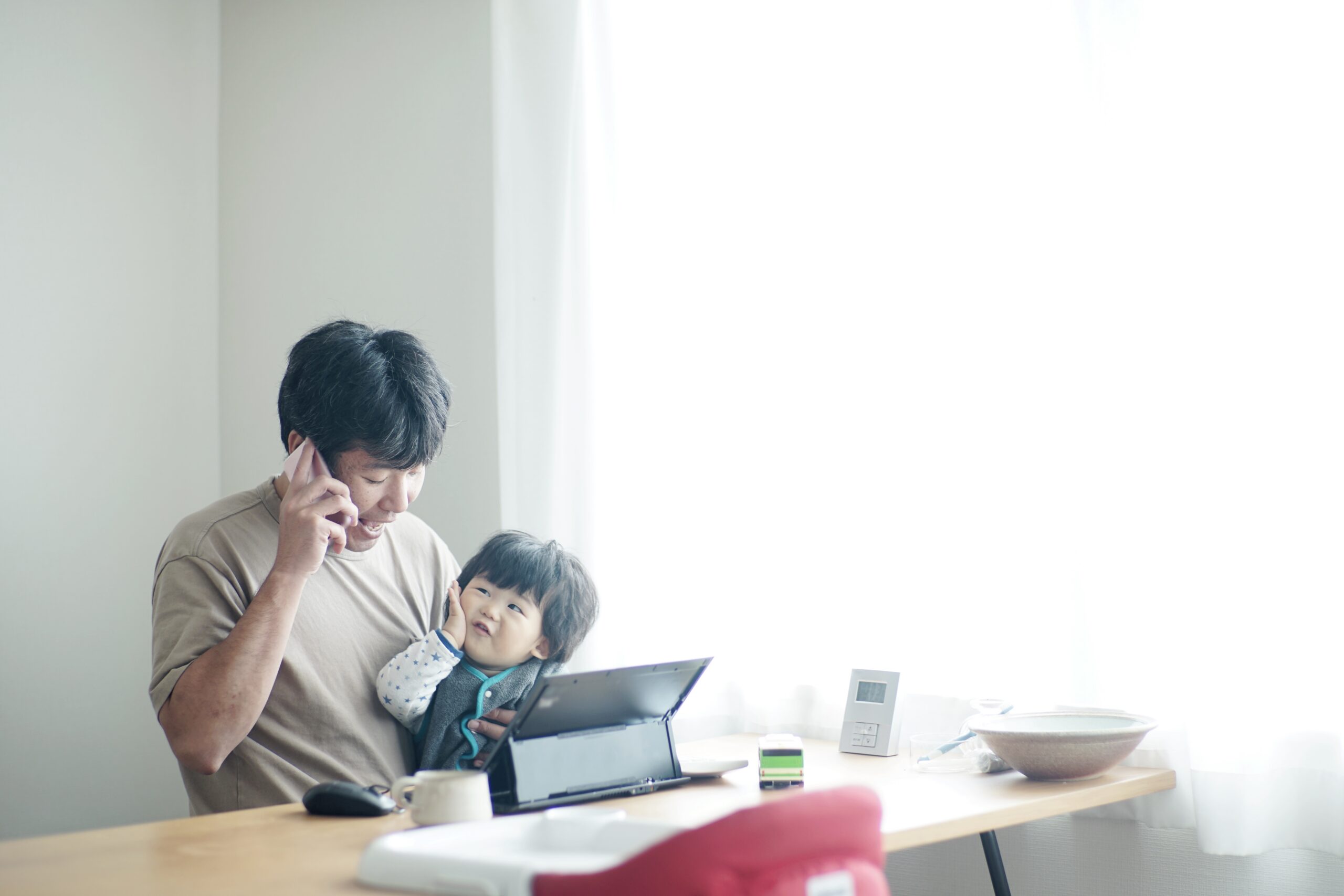 子供を膝に乗せて在宅勤務をする父親
