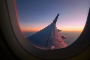 Blick aus einem Flugzeugfenster mit Sonnenuntergang im Hintergrund