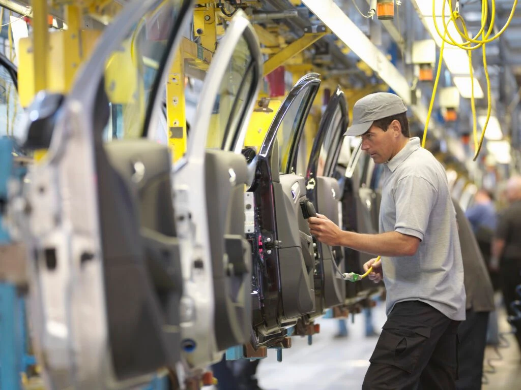 Mitarbeiter arbeitet an einer Fahrzeugmontage-Linie in einer modernen Autofabrik